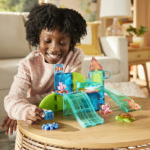 Child playing with a colorful toy set on a wooden table in a living room.