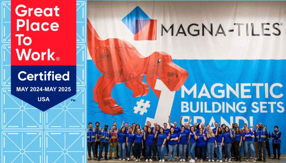 Group of Magna-Tiles employees posing in front of a large MAGNA-TILES banner with a red dinosaur and a Great Place To Work certified badge