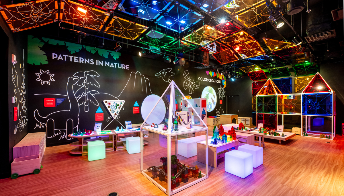 Studio interior with colorful clear tile structures, lit ceiling panels, and wall text Patterns in Nature and Color Creations
