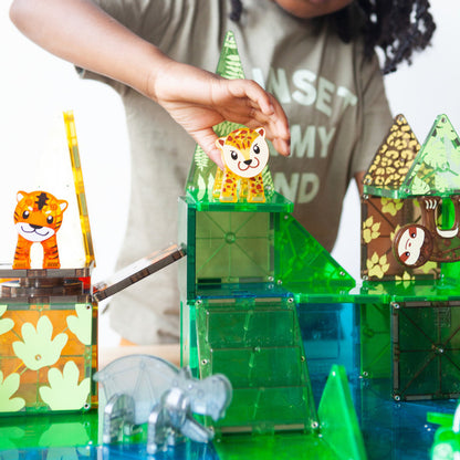 Child placing a giraffe figure on a colorful MAGNA-TILES jungle habitat