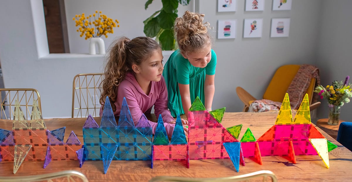 Two children playing with MAGNA-TILES® Color Shop products on a table