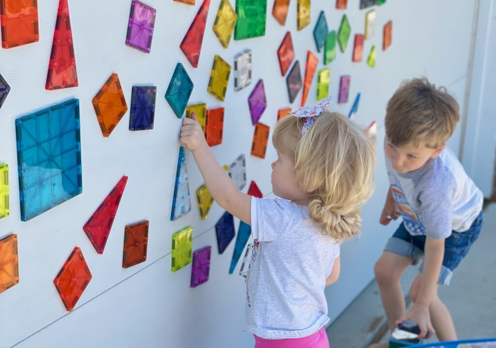 Children playing with MAGNA-TILES pieces on a garage door
